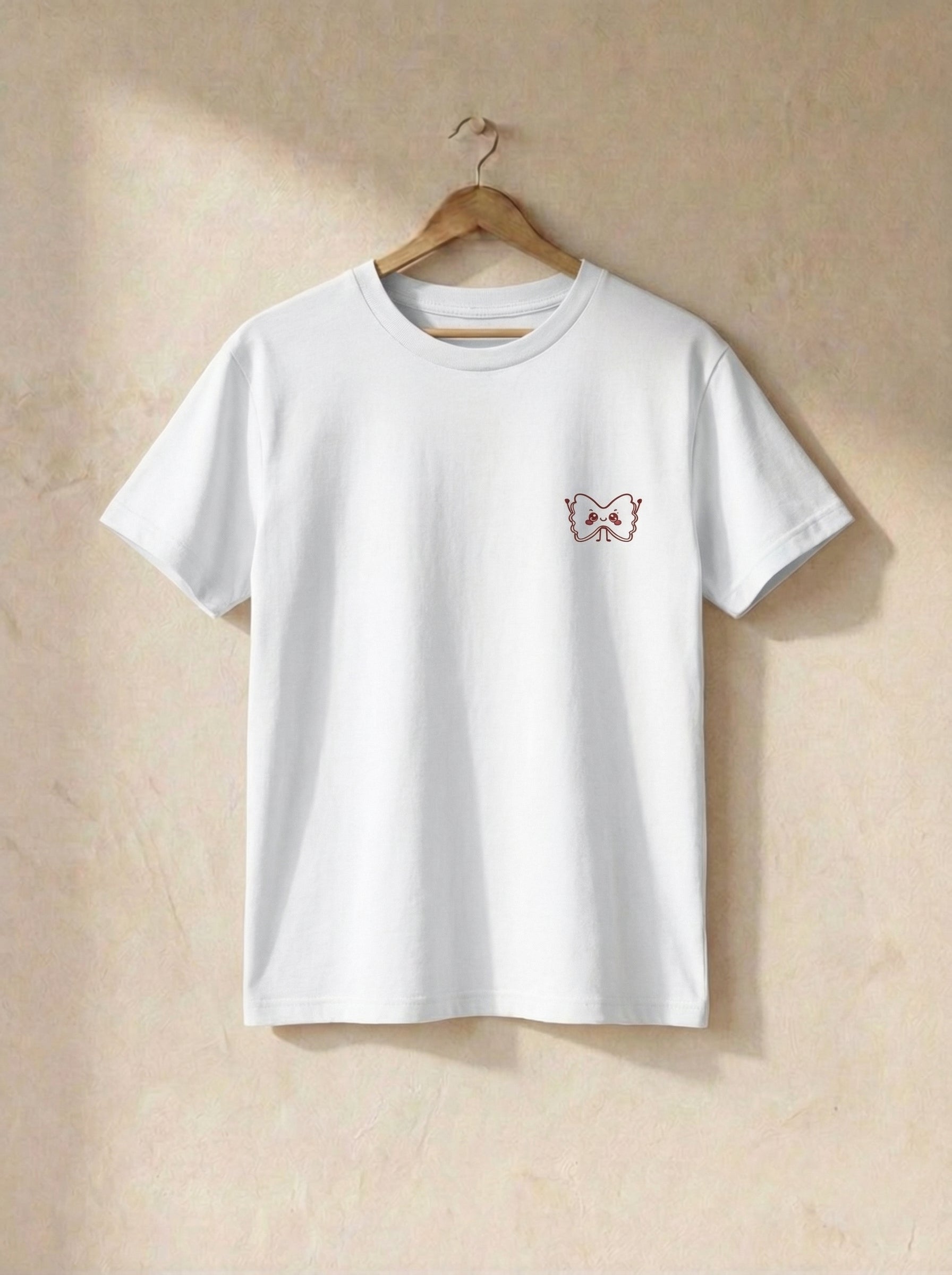 White t-shirt with a small design on a wooden hanger against a beige wall.