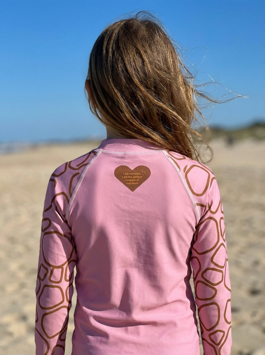 Person wearing a pink long-sleeve shirt with heart patterns on a beach