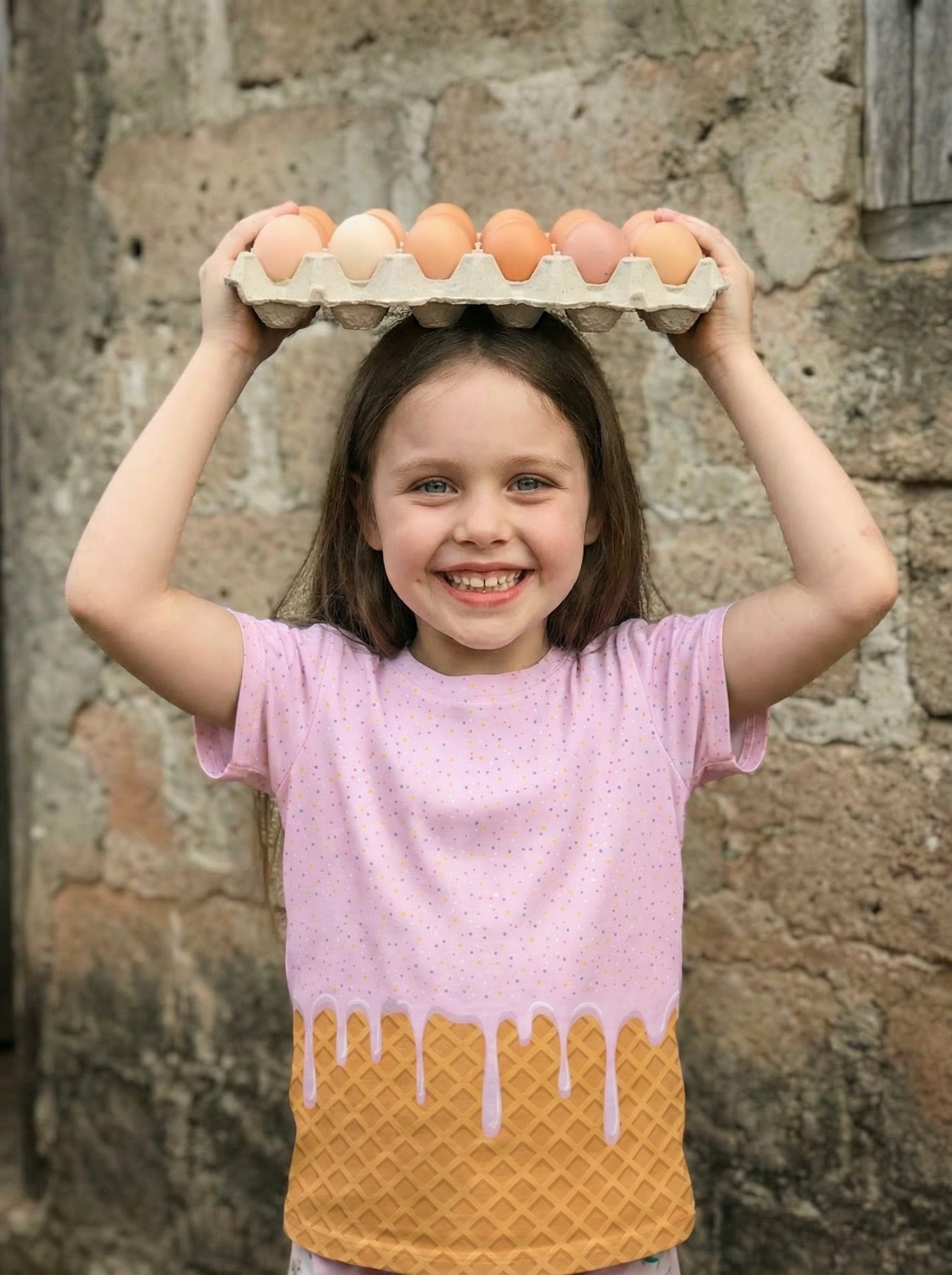 Child holding a carton of eggs on their head against a stone wall.