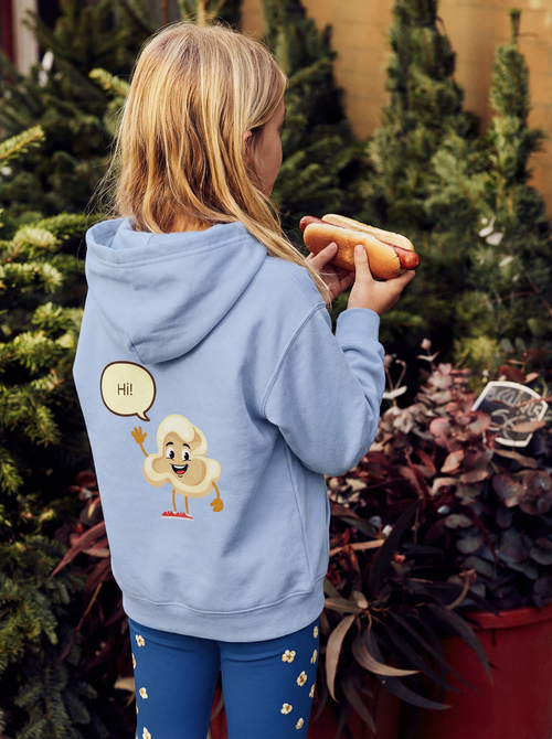 Person wearing a light blue hoodie with a cartoon character design, holding a hot dog outdoors.
